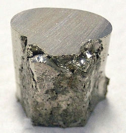 A pitted and lumpy piece of silvery metal, with the top surface cut flat